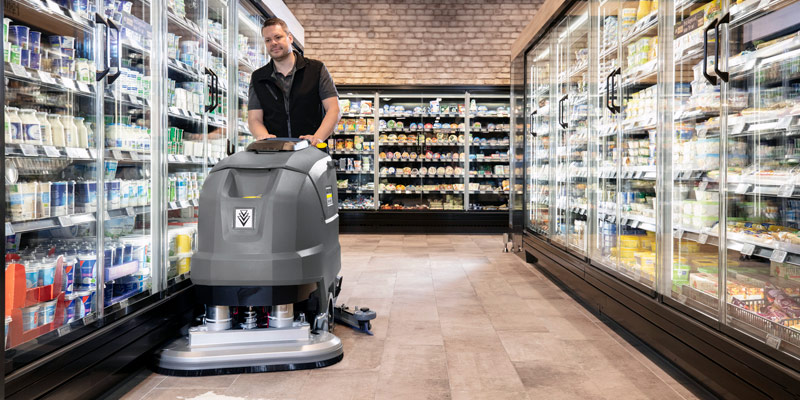 Profissional lavando piso de supermercado com equipamento