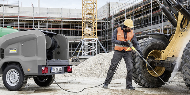 Person rengører gravemaskine med Kärcher professionel højtryksrenser