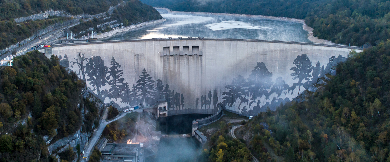 Dem Himmel so nah - Ein Kunstrprojekt der Superlative Staudamm in Vouglans in Frankreich der ein Reverse Graffiti Kunstwerk von Künstler Klaus Dauven zeigt. Eine Waldlandschaft.