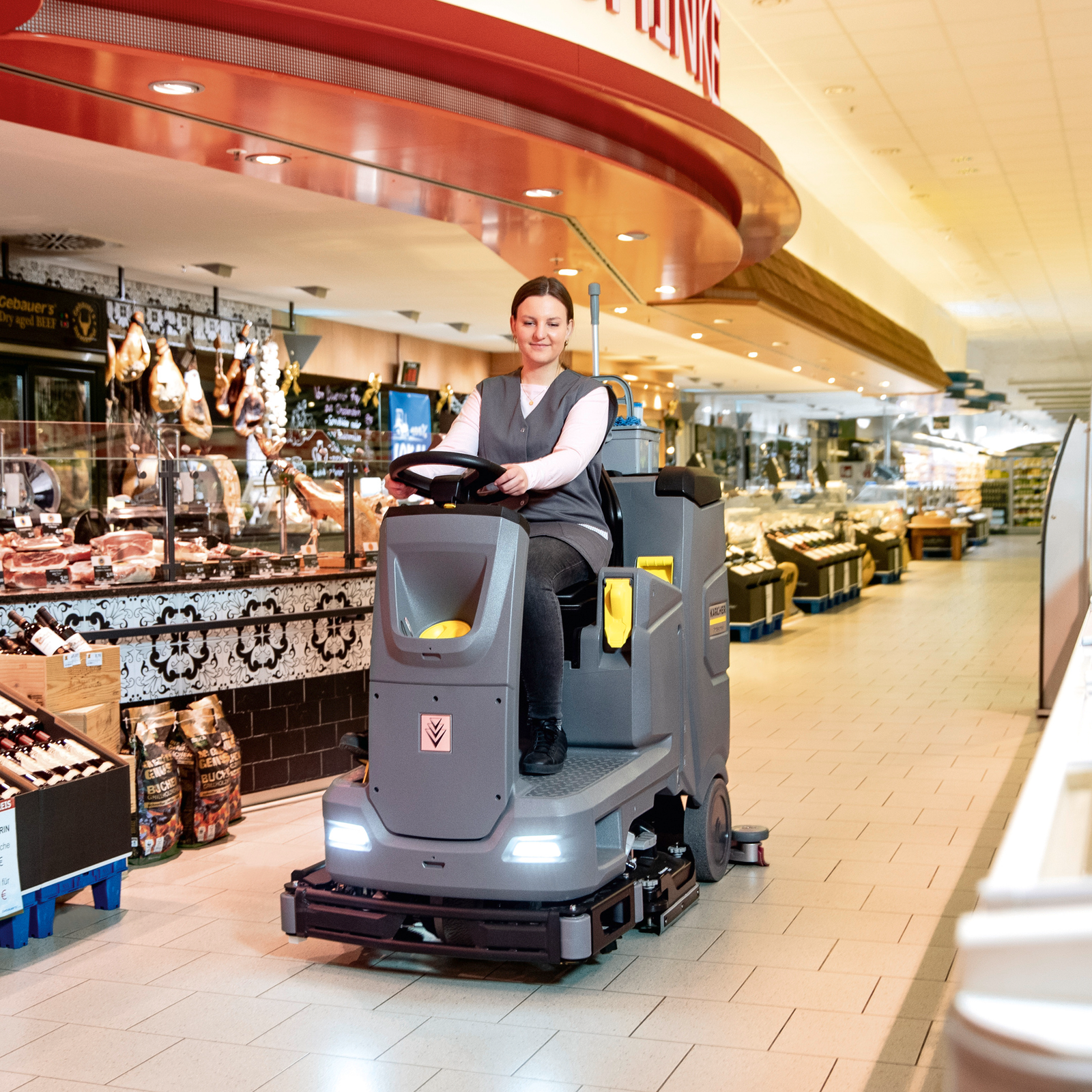Frau sitzt auf Scheuersaugmaschine im Einzelhandel. Frau sitzt auf Scheuersaugmaschine im Einzelhandel.