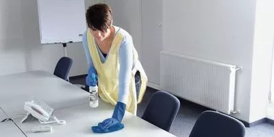 Person disinfecting a table in a conference room