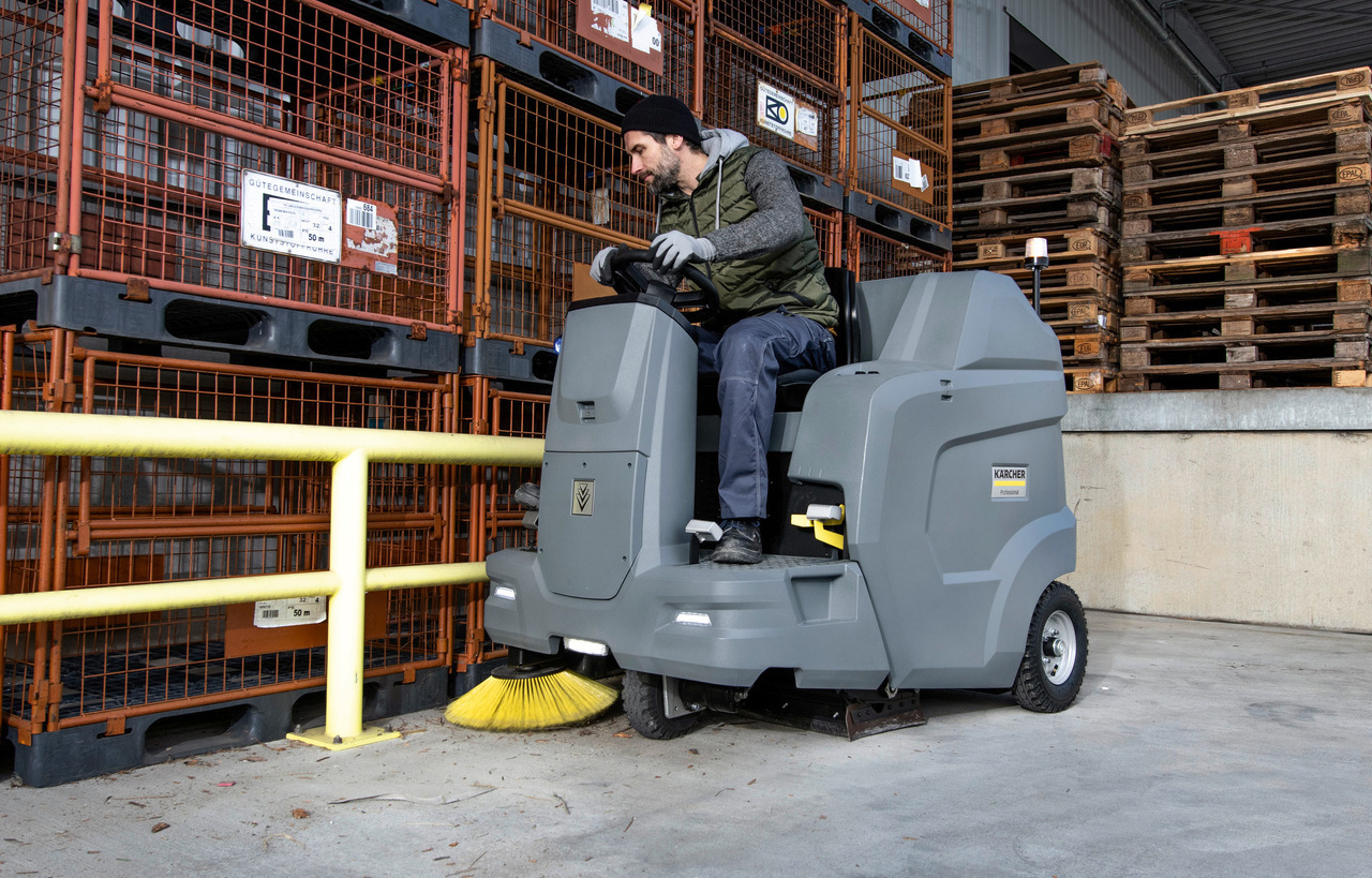 Aufsitz-Kehrsaugmaschine im Einsatz Ein Mann reinigt mit einer Kärcher Aufsitz-Kehrsaugmaschine eine Lagerhalle