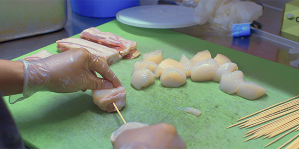 Food Prep Areas & Equipment A line chef skewers scallops in a food prep area.