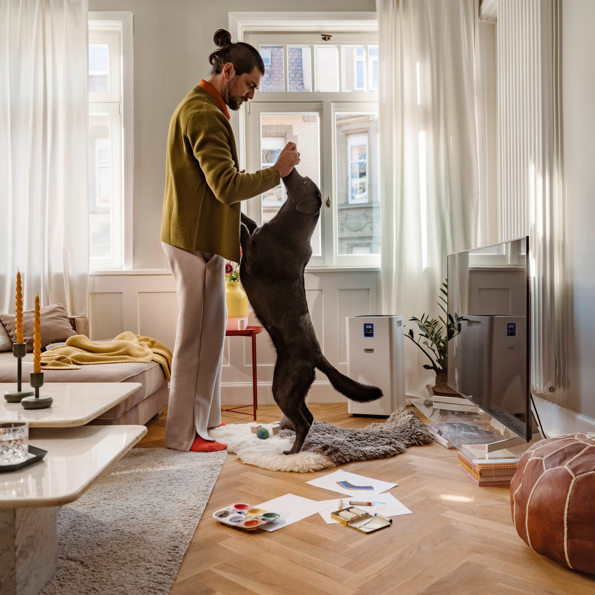 Een persoon is met zijn hond aan het spelen in de woonkamer Kärcher luchtreiniger