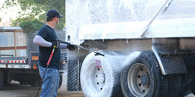 Provides the Most Effective Cleaning A worker pressure washes tires on a truck