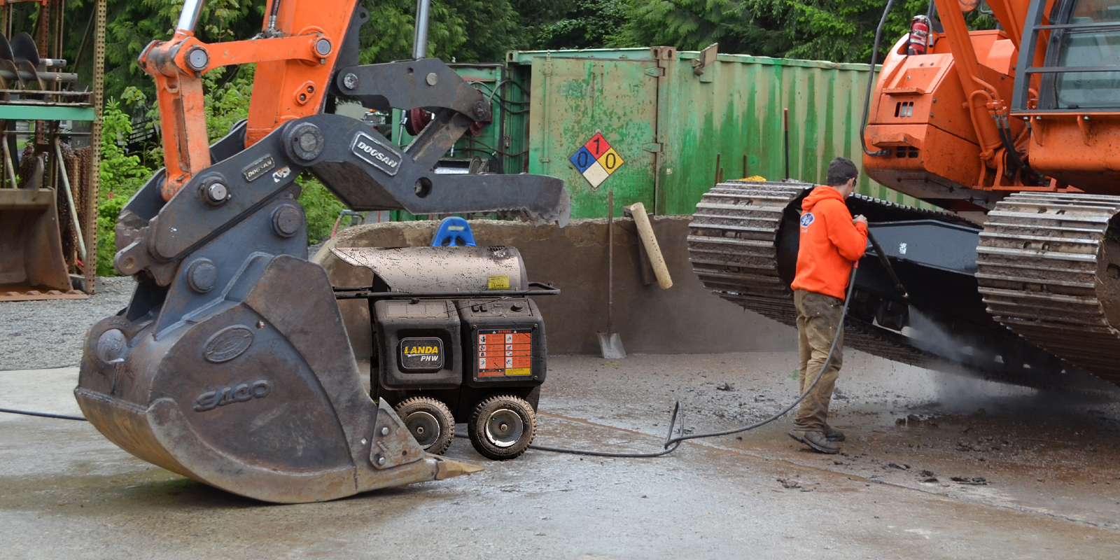 Portable Electric Hot Water Pressure Washers A worker cleans construction equipment using a Landa PHW electric hot water pressure washer.
