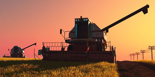 Agriculture Industry A combine harvester runs in a field at dusk.