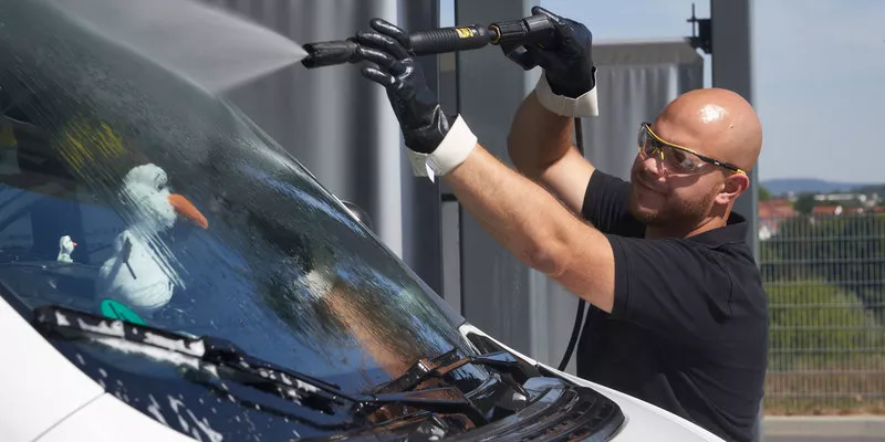 Ένας άντρας καθαρίζει το παρμπρίζ του τροχόσπιτου του με ένα πλυντήριο πίεσης Kärcher