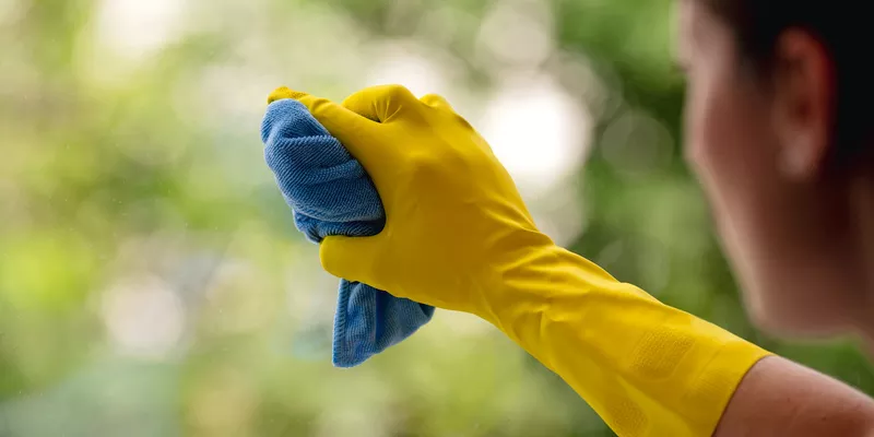 Μια γυναίκα καθαρίζει ένα παρμπρίζ χρησιμοποιώντας ένα γάντι και ένα πανί