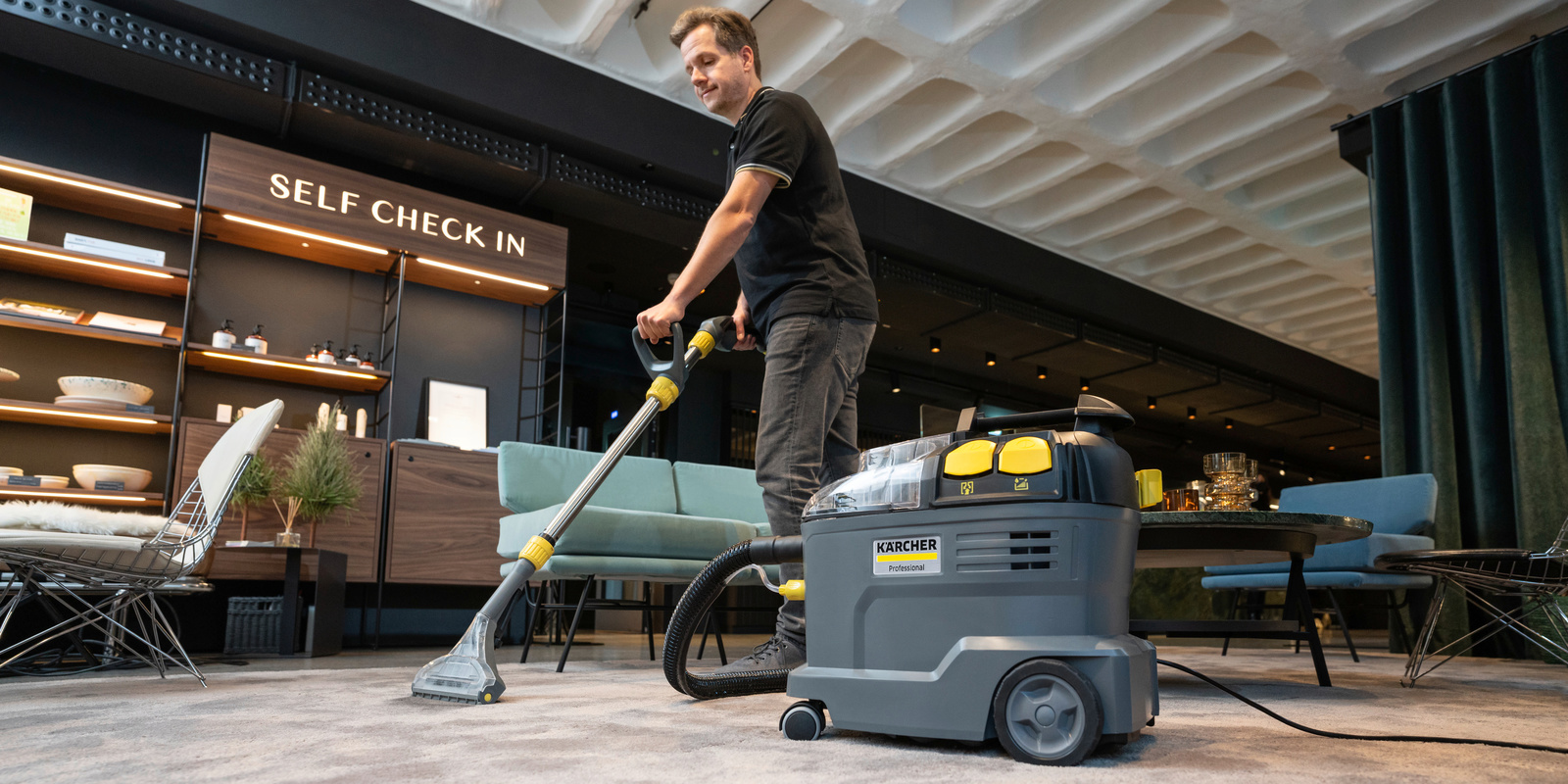 Teppichbodenreinigung in der Hotel-Lobby Ein Mann reinigt in der Hotel-Lobby den Teppich mit einem Kärcher Sprühextraktionsgerät
