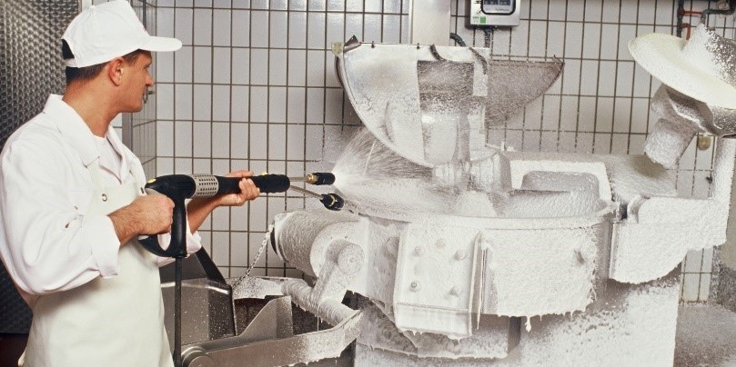 Cleaning machines with high pressure washers in a butcher’s shop A man in white work clothes sprays a butcher machine using a Kärcher pressure washer