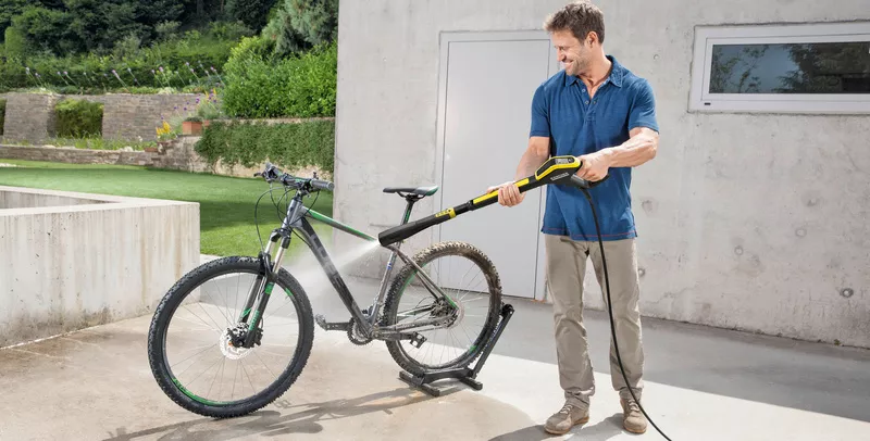 Ένας άντρας καθαρίζει το ποδήλατο βουνού του με ένα πλυντήριο πίεσης Kärcher