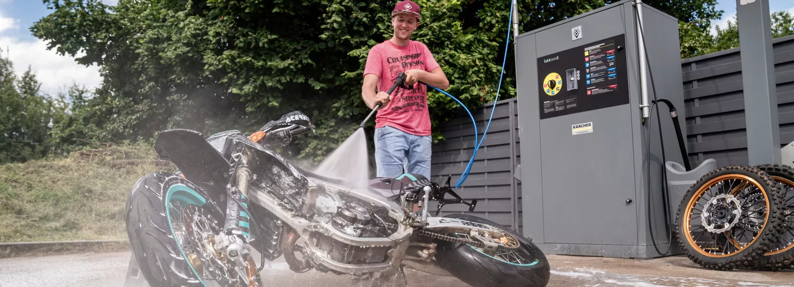 Ένας άντρας καθαρίζει την ξαπλωμένη μοτοσυκλέτα του σε ένα κουτί πλυσίματος Kärcher