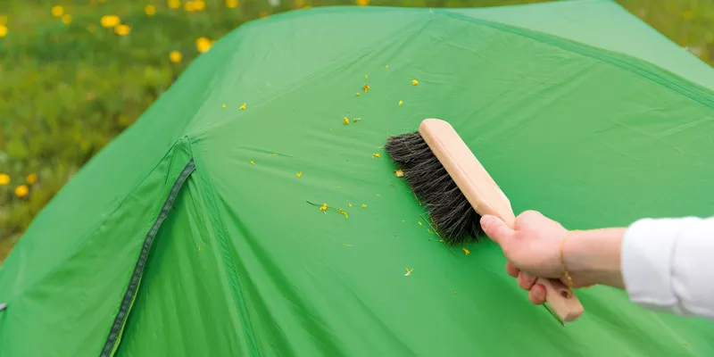 A tent is cleaned and dirt removed with a broom