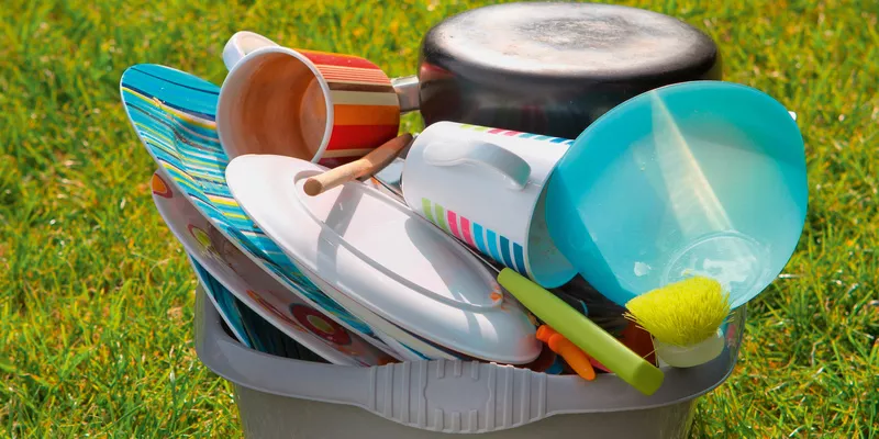 Camping tableware on the lawn in a bowl