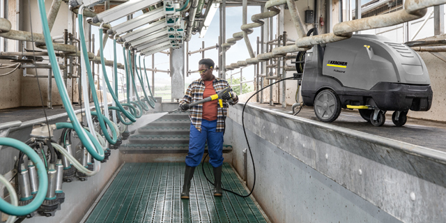 Decrease Use of Detergents and Fewer Germs A worker uses a Kärcher pressure washer to clean a milking parlor