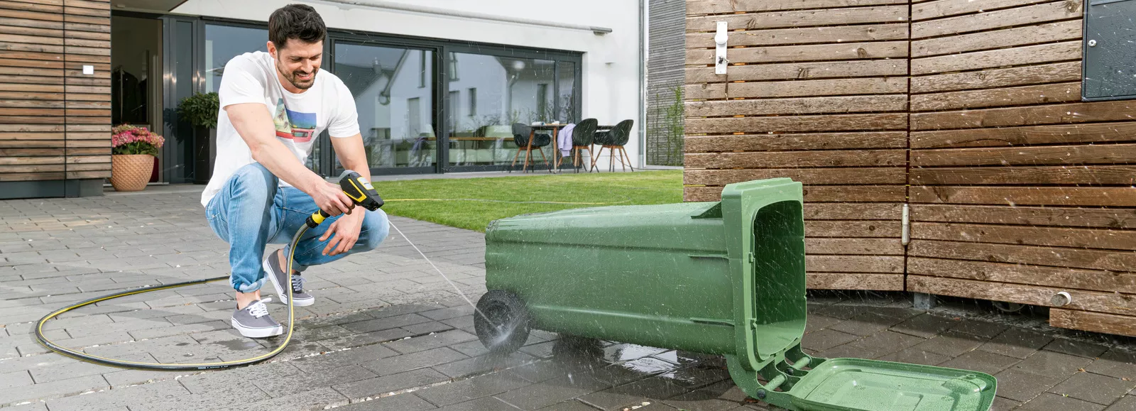A man cleans a bin with the Kärcher waterbooster