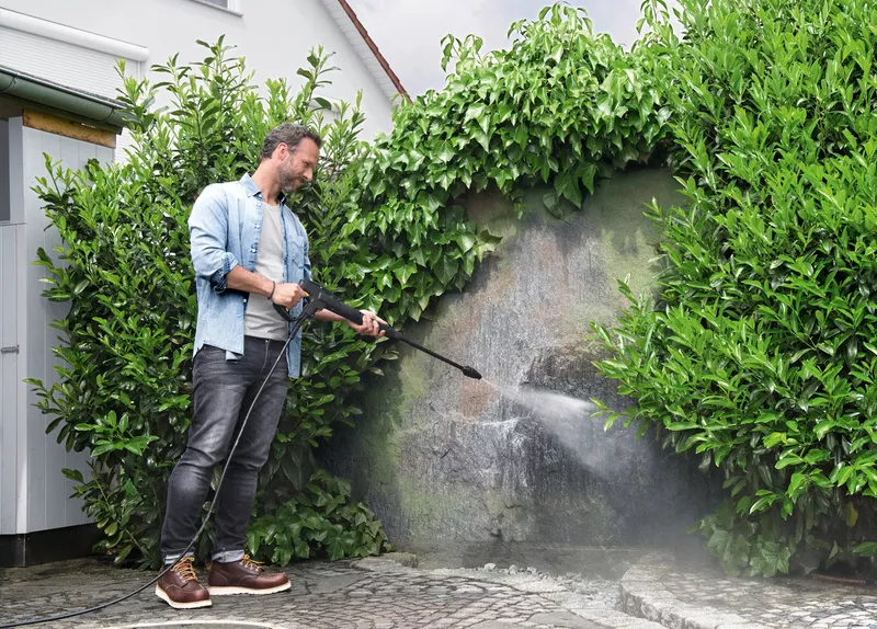 Ένας άντρας αφαιρεί βρύα σε έναν τοίχο με ένα πλυντήριο πίεσης Kärcher