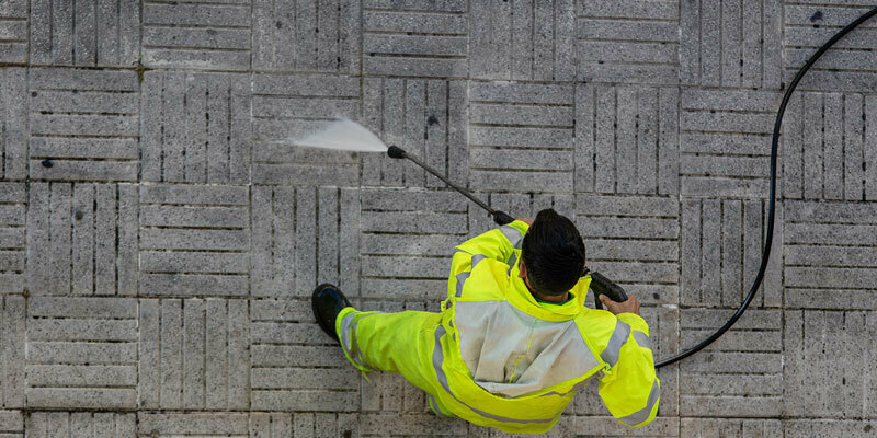Engines Subject to SORE Regulations Overhead view of a worker cleaning pavement with a Hotsy pressure washer
