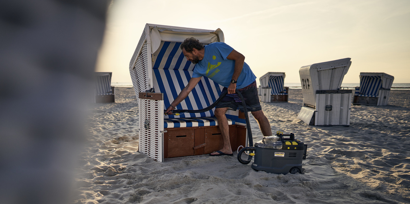 Un homme nettoie un fauteuil-cabine de plage avec le Kärcher Puzzi 9/1 Bp Un homme nettoie un fauteuil-cabine de plage avec le Kärcher Puzzi 9/1 Bp