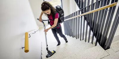 Cleaning a stairwell with a Kärcher battery-powered backpack vacuum.