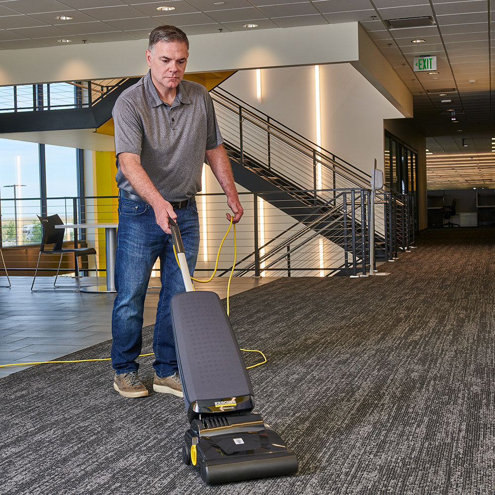 Vacuuming carpets in an office building Man uses the Kärcher Ranger upright vacuum to clean office carpets