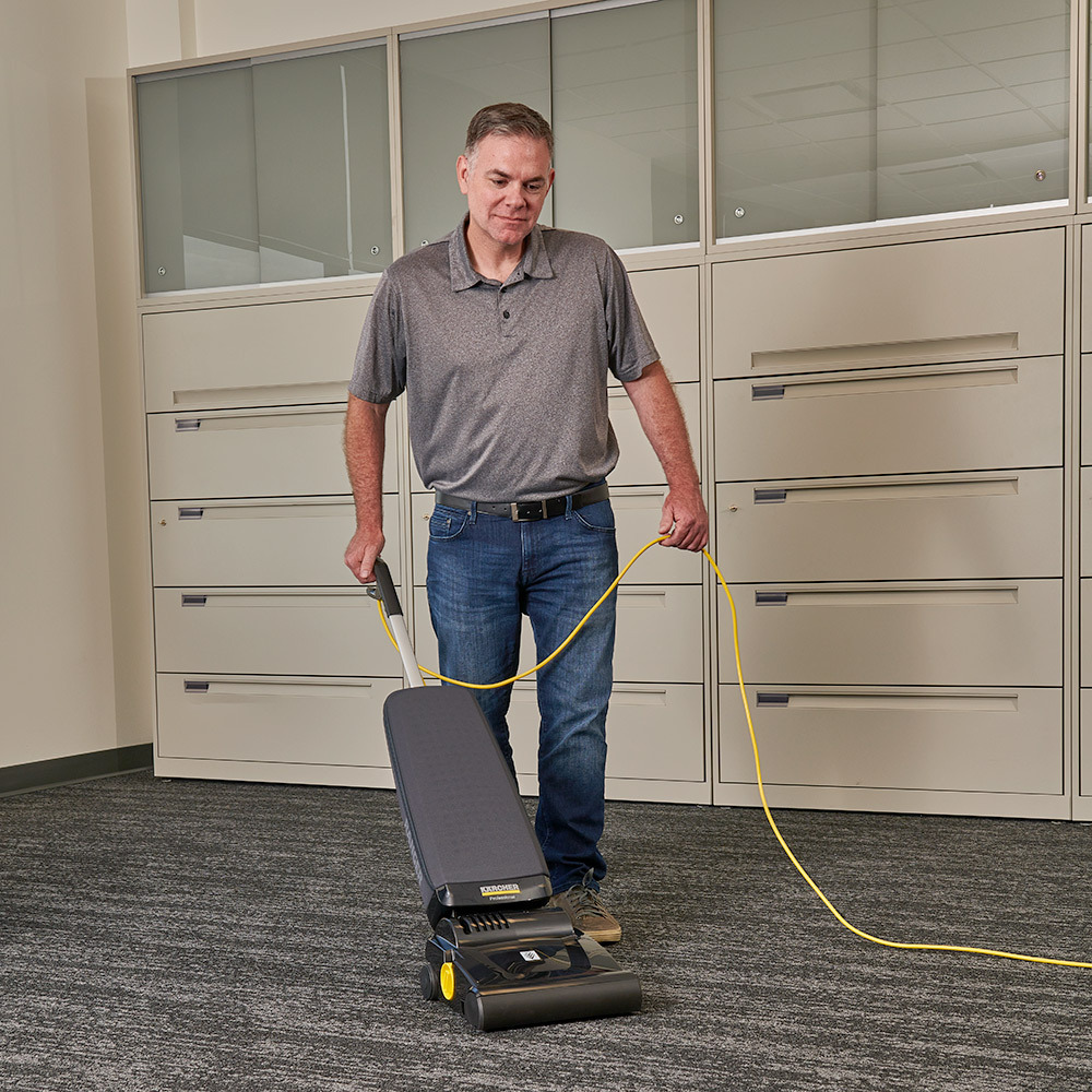 Hotel business center vacuuming Man cleans carpeted floors in a hotel business center
