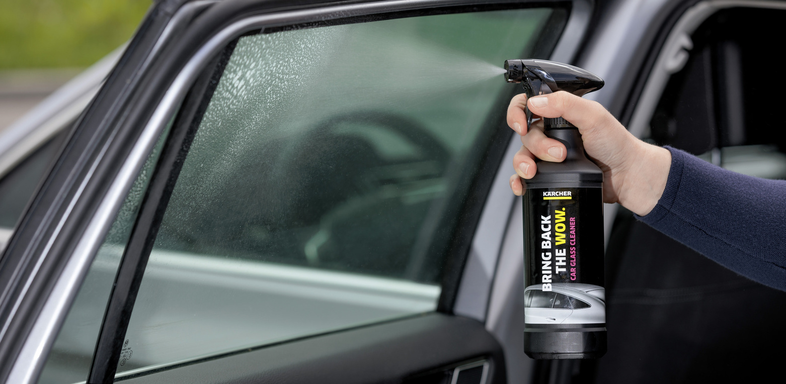 Nettoyer les vitres de la voiture avec un nettoyant spécial pare-brise Le nettoyant spécial pare-brise Kärcher se vaporise sur les vitres de la voiture