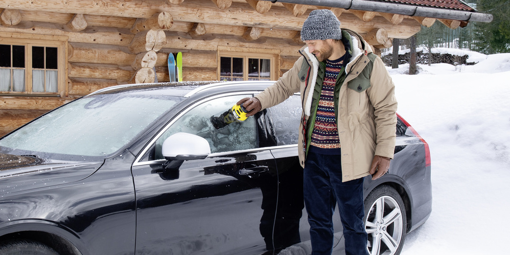 Un homme dégivre sa voiture dans la neige