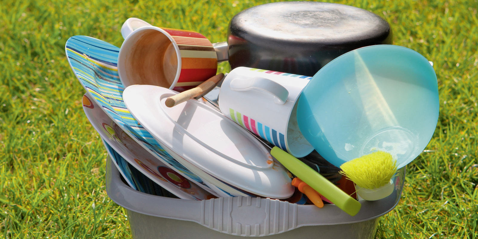 Laver la vaisselle de camping Vaisselle de camping dans un bac sur l’herbe