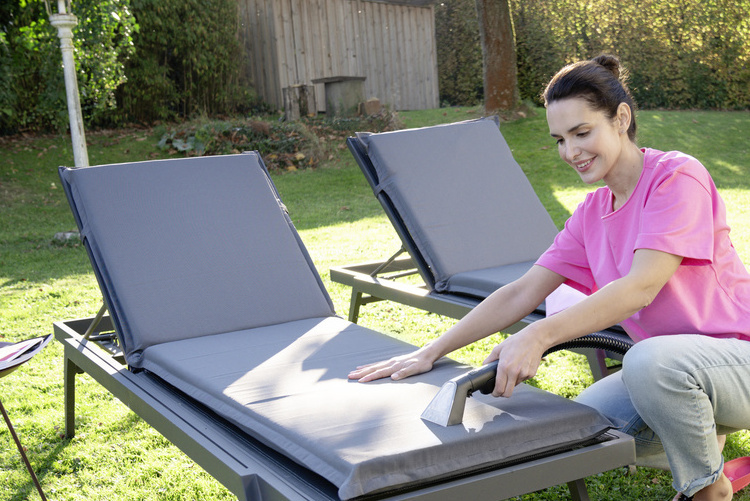 Nettoyer le mobilier de jardin en tissu Une femme nettoie les coussins en tissu de ses chaises longues de jardin