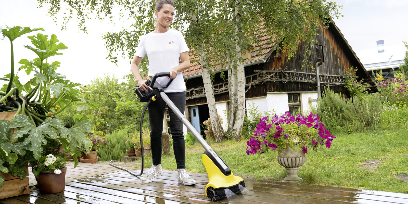 Nettoyer une terrasse en bois avec un nettoyeur de terrasse Une femme nettoie sa terrasse en bois avec un nettoyeur de terrasse Kärcher