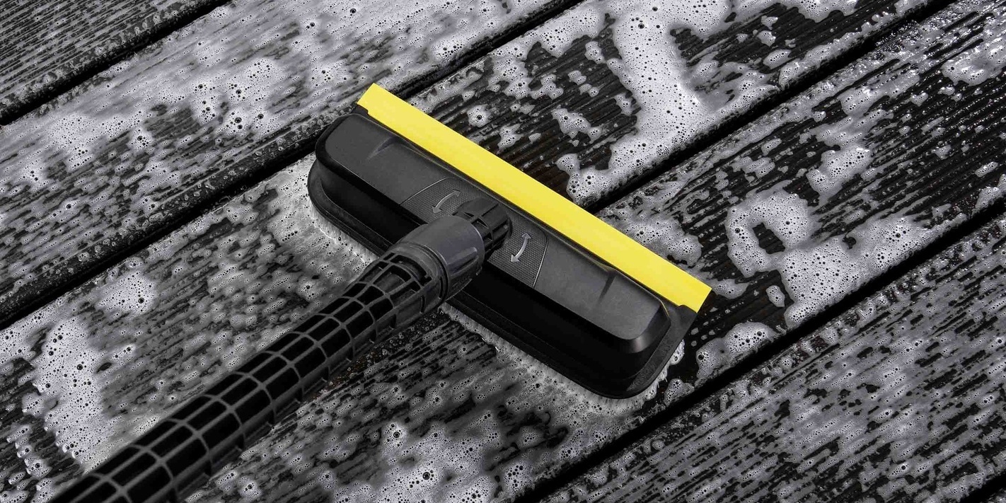 Nettoyer une terrasse en bois avec une brosse nettoyante haute performance Une brosse nettoyante haute performance Kärcher en train de nettoyer une terrasse en bois