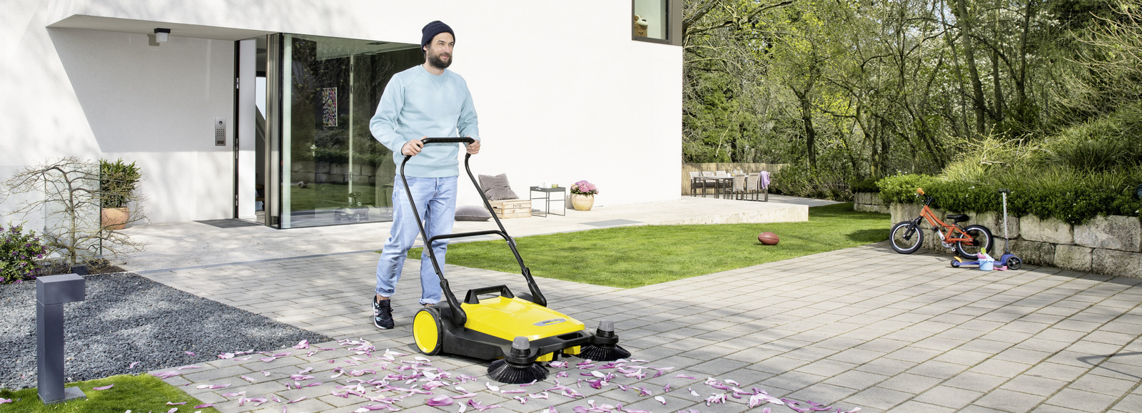 Nettoyer les pavés avec une balayeuse Un homme nettoie les pavés avec une balayeuse Kärcher au printemps