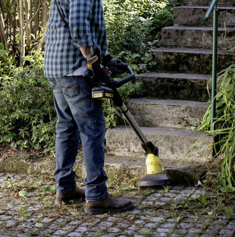 Nettoyer les joints Un homme portant des écouteurs nettoie les joints des pavés devant un escalier avec un désherbeur Kärcher.