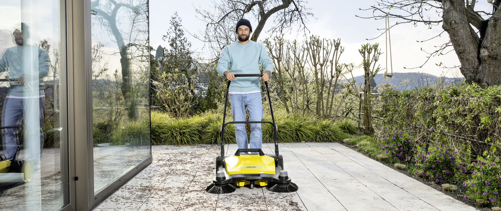 Nettoyer les dalles de terrasse avec une balayeuse Un homme nettoie une terrasse avec une balayeuse Kärcher