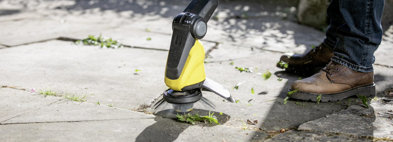 Nettoyer les terrasses avec un désherbeur sans fil Kärcher: un homme nettoie des dalles de terrasse avec un désherbeur sans fil