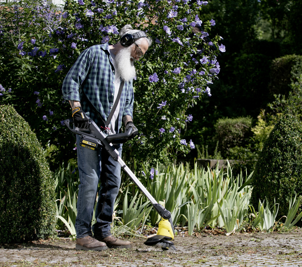 Éliminer efficacement les mauvaises herbes Un homme nettoie une terrasse avec son désherbeur Kärcher