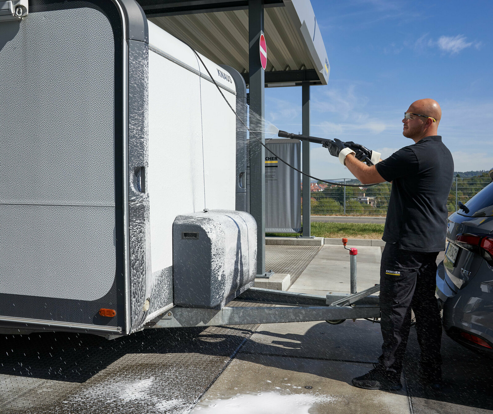 Nettoyer sa caravane Un homme nettoie l’avant de sa caravane avec un nettoyeur haute pression Kärcher
