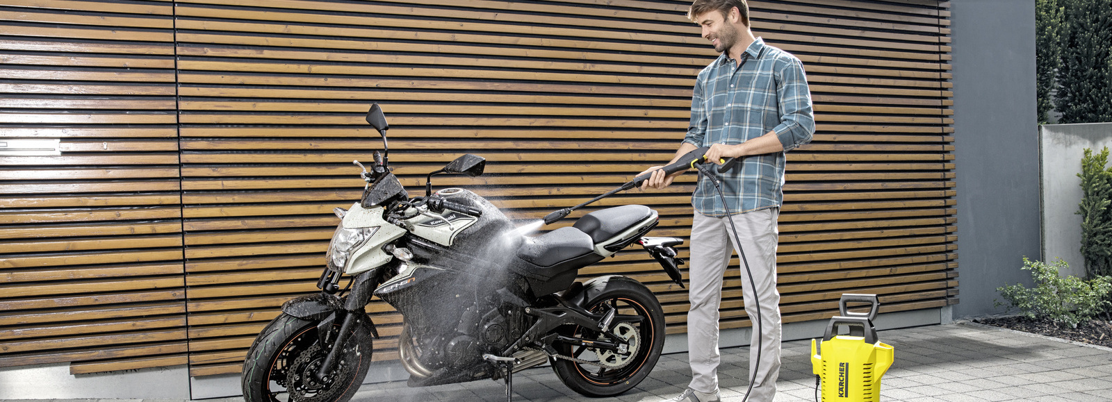 Nettoyer sa moto Un homme nettoie sa moto avec un nettoyeur haute pression Kärcher