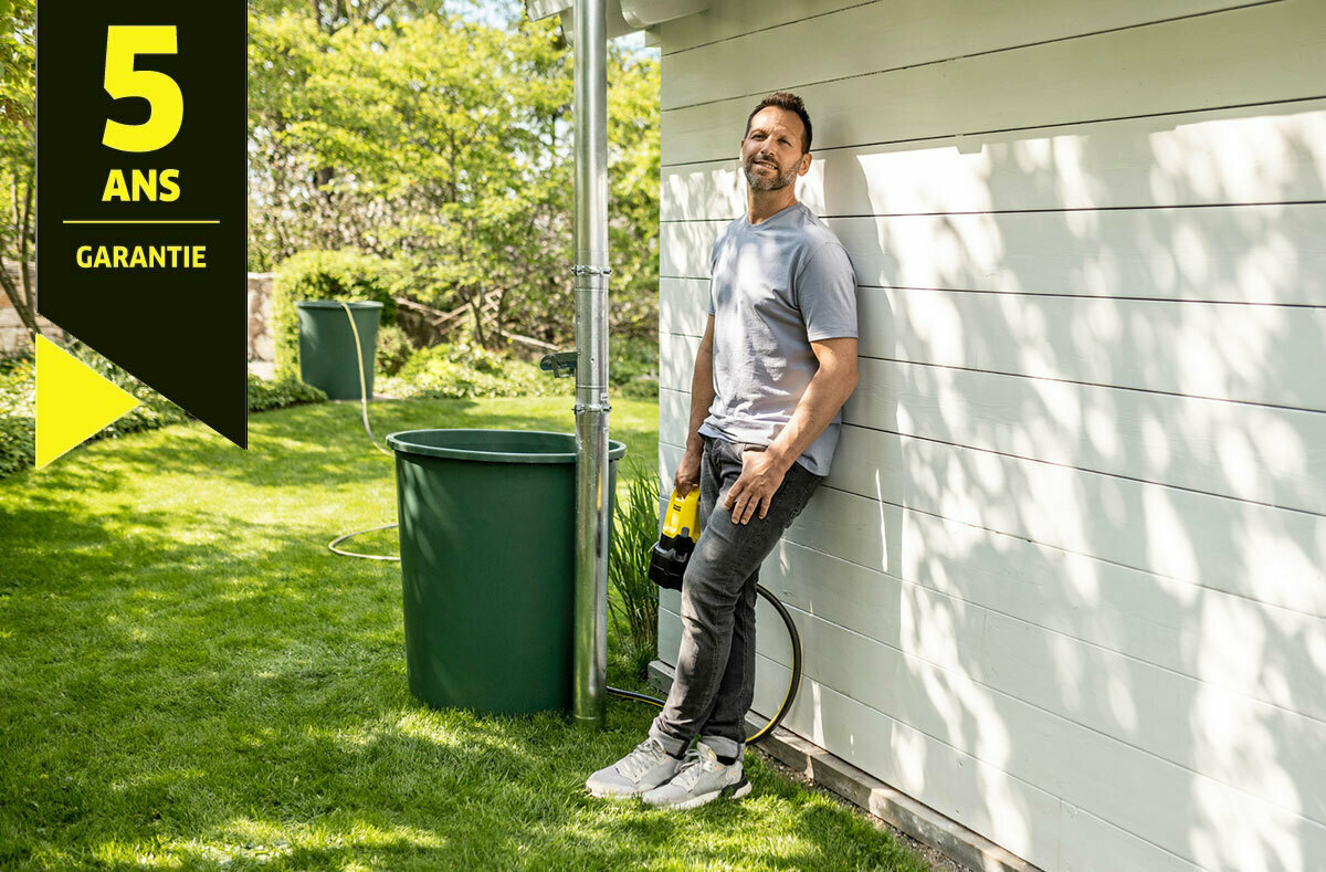 Homme appuyé contre un mur avec une pompe à eau en main