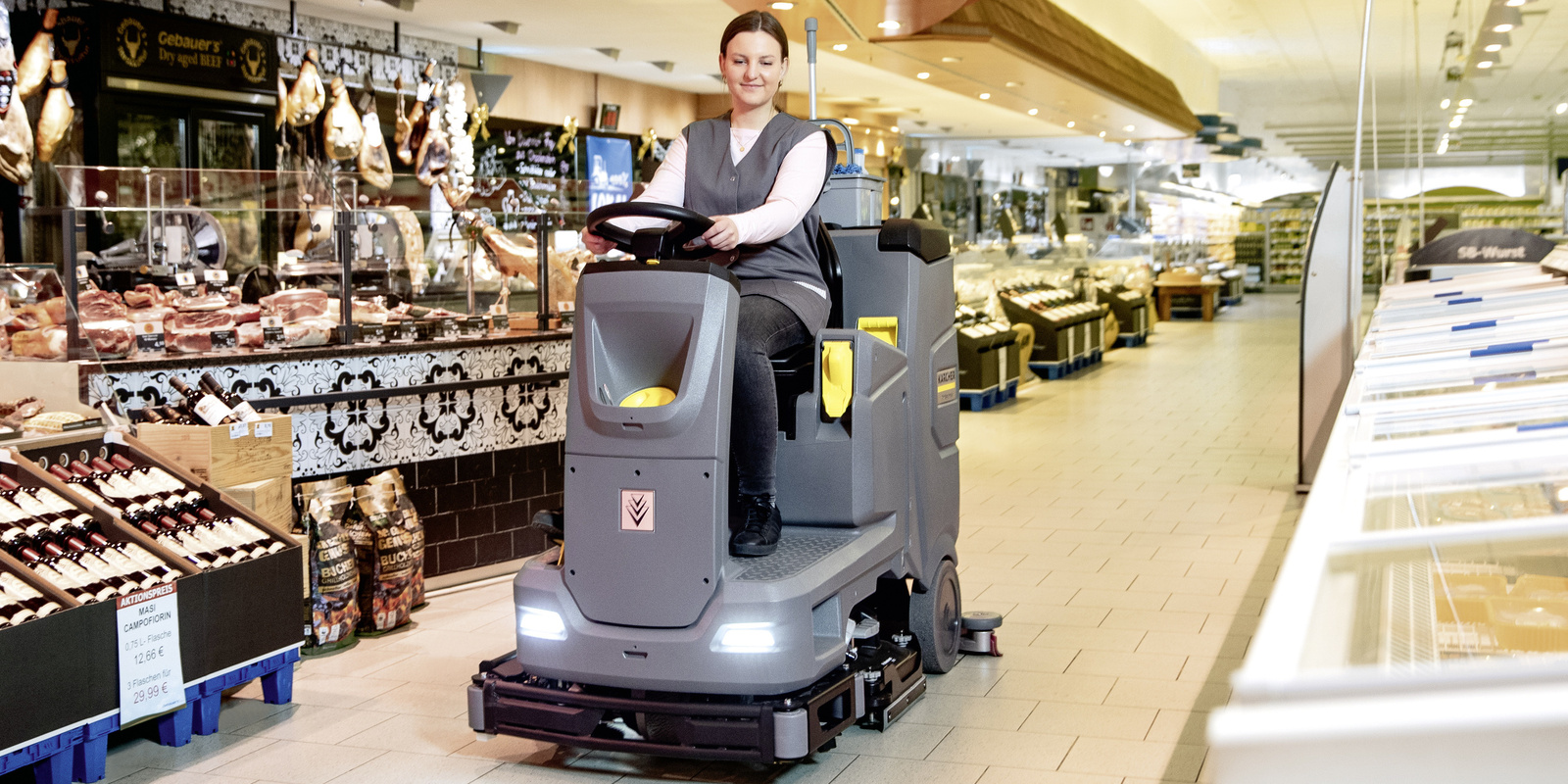 Leasing in the cleaning industry A person sits on a Kärcher sweeper machine cleaning the floor of a supermarket