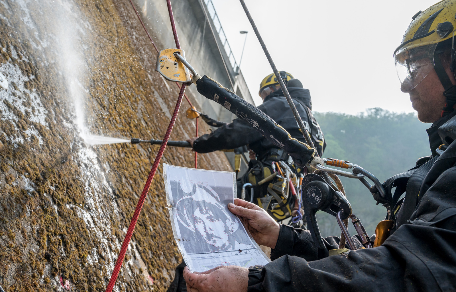 Des grimpeurs apposent le Reverse graffiti sur le barrage. Des grimpeurs apposent le Reverse graffiti sur le barrage.