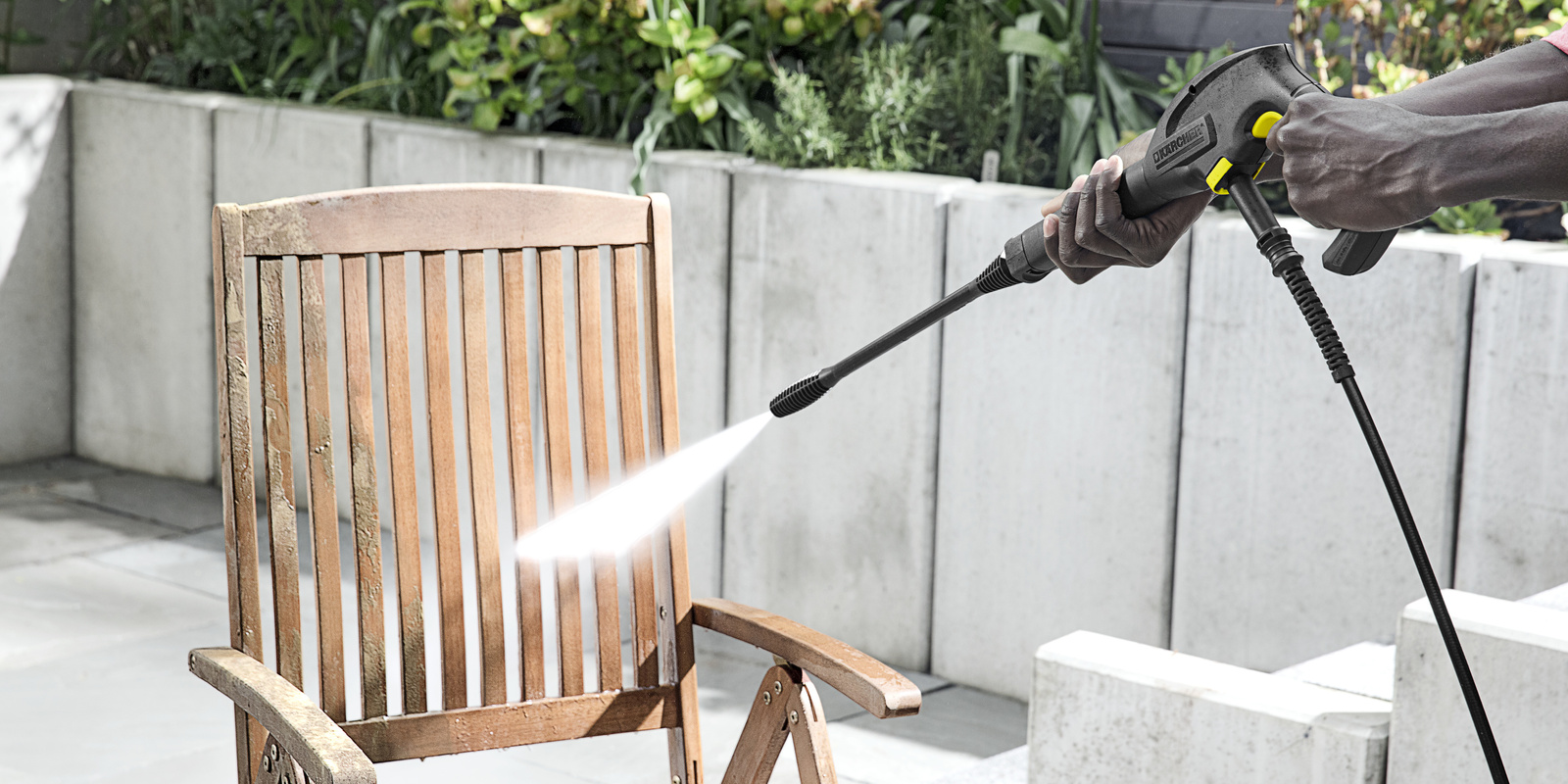 Man is cleaning garden furniture with a Kärcher pressure washer