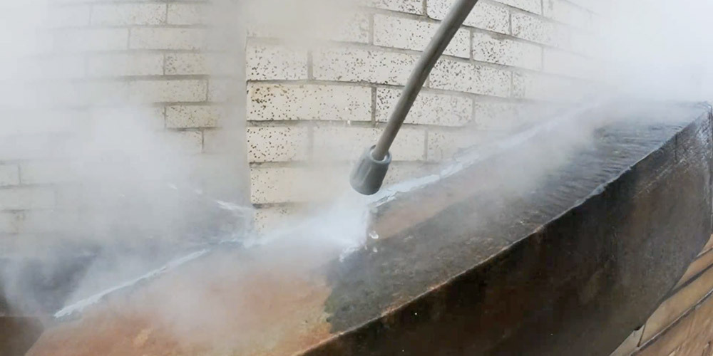Algae, lichen and fungi are pressure washed from the facade A close-up shot of a pressure washer wand clearing biological materials from the building exterior