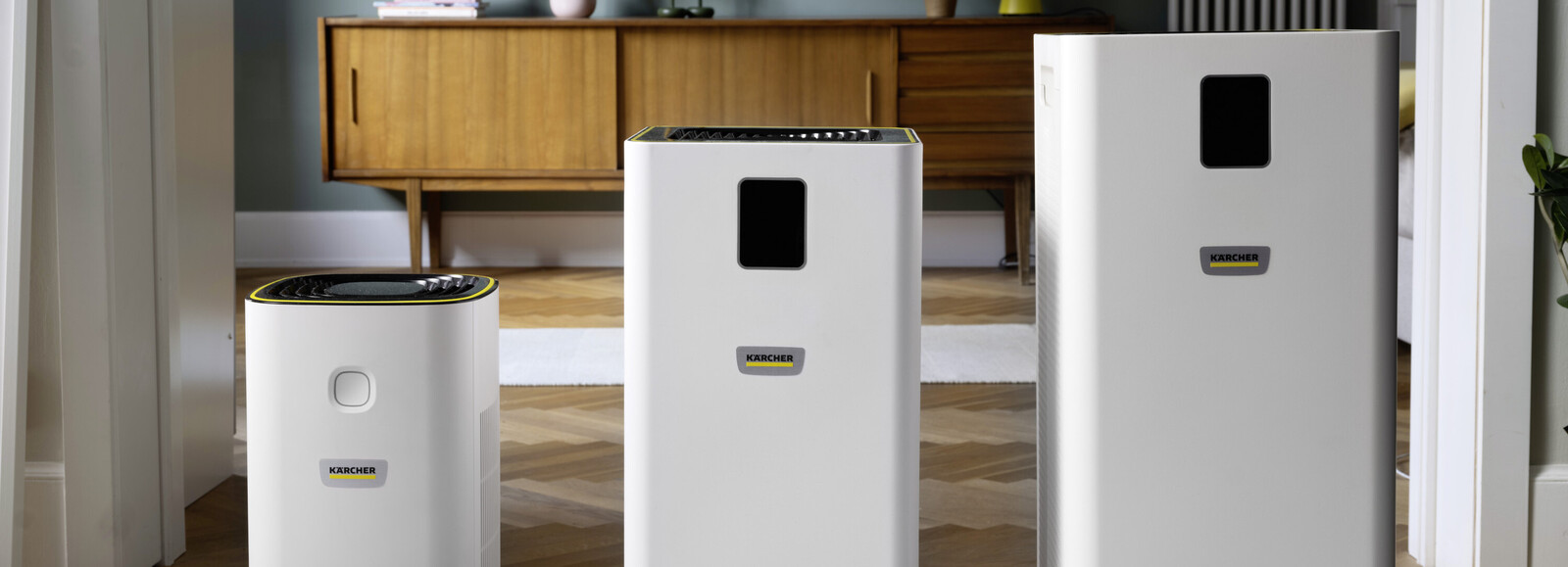 Trzy modele oczyszczaczy powietrza Kärcher z serii AF obok siebie na tle pokoju.