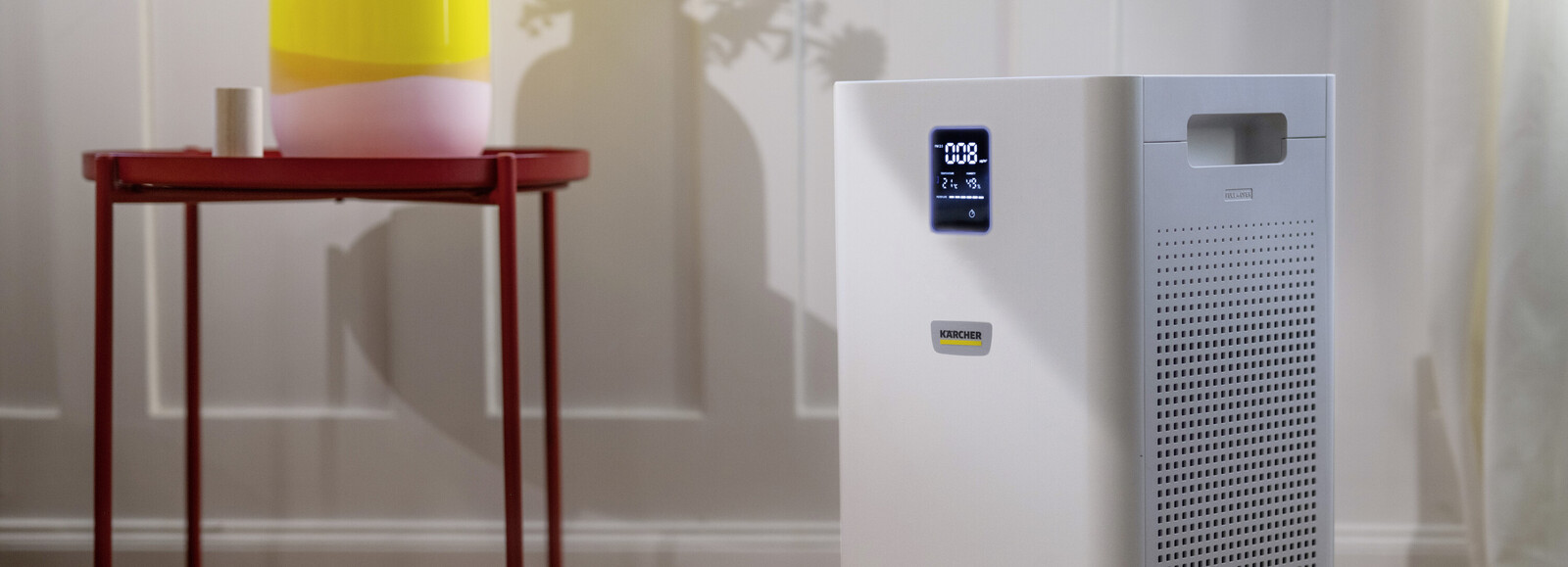 Oczyszczacz powietrza Kärcher AF 50 ustawiony w pokoju obok stolika z wazonem.