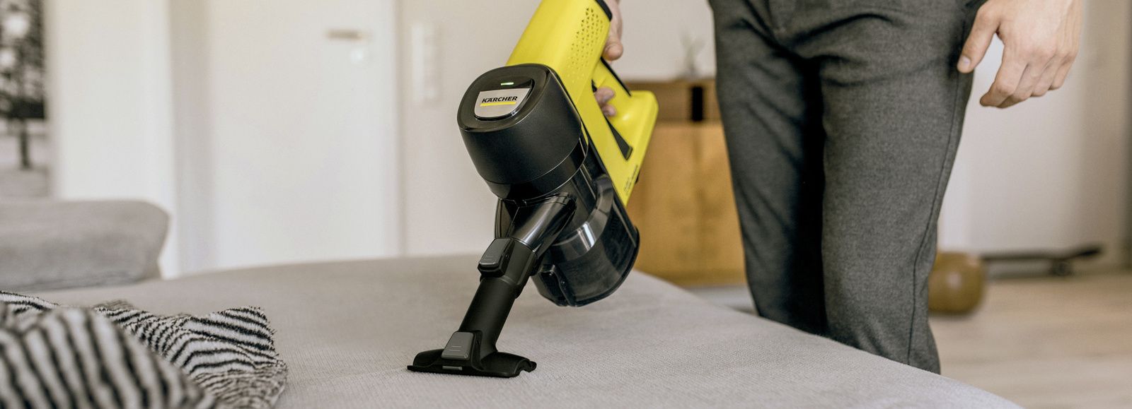 Odkurzanie kanapy za pomocą odkurzacza pionowego Karcher wyposażonego w ssawkę do tapicerki. Odkurzanie kanapy za pomocą odkurzacza pionowego Karcher wyposażonego w ssawkę do tapicerki.