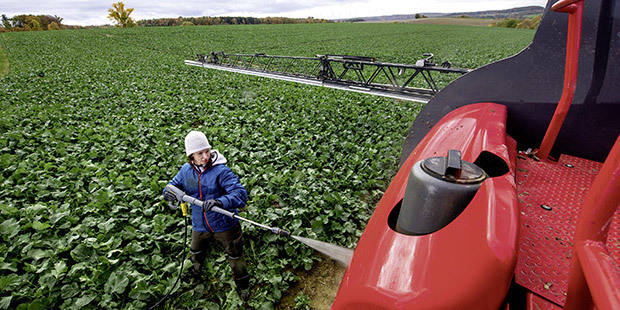 Cold Water Battery Pressure Washers A worker cleans farming equipment using a Kärcher Cold Water Battery Pressure Washer