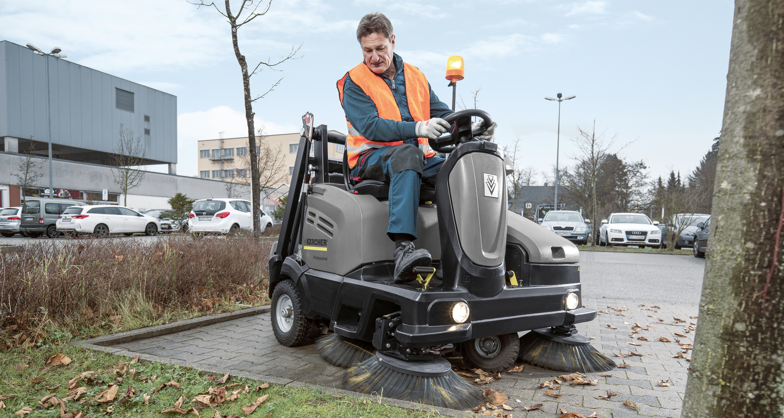 Parkplätze reinigen Eine Person bedient eine Aufsitz-Kehrmaschine